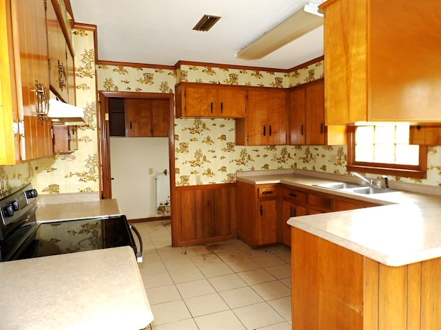 kitchen with electric range oven, kitchen peninsula, sink, and light tile patterned floors