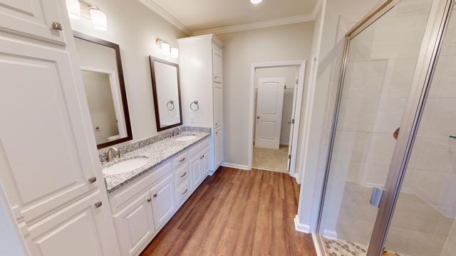 bathroom featuring hardwood / wood-style flooring, vanity, an enclosed shower, and crown molding