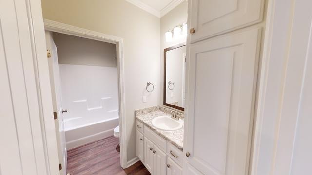 bathroom featuring hardwood / wood-style flooring, vanity, toilet, and ornamental molding