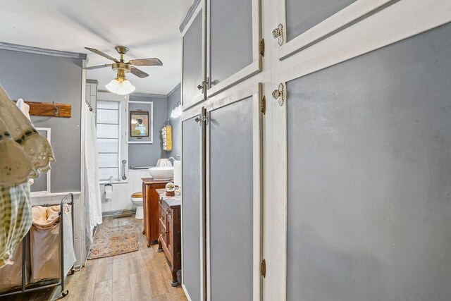 bathroom with ornamental molding, toilet, wood finished floors, vanity, and a ceiling fan