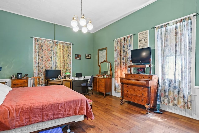 bedroom featuring a notable chandelier, crown molding, and wood finished floors