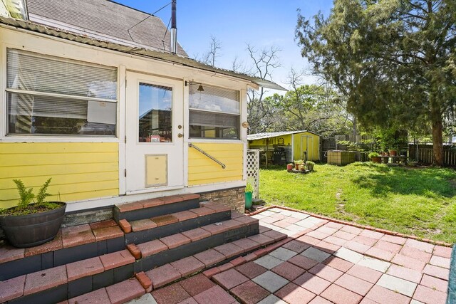view of patio / terrace featuring an outbuilding, a shed, fence, and entry steps