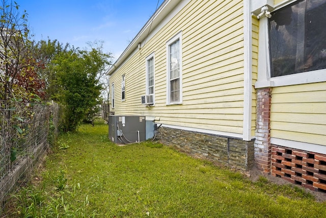 view of side of home featuring a yard, central AC, and fence