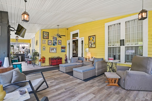 living room with lofted ceiling, wooden walls, wood finished floors, and a ceiling fan