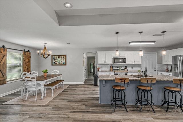 kitchen featuring arched walkways, baseboards, white cabinetry, and appliances with stainless steel finishes