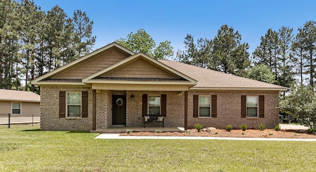 view of front of home with a porch, roof with shingles, fence, brick siding, and a front lawn