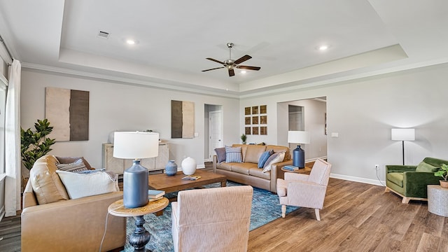 living room featuring hardwood / wood-style floors, ceiling fan, and a tray ceiling