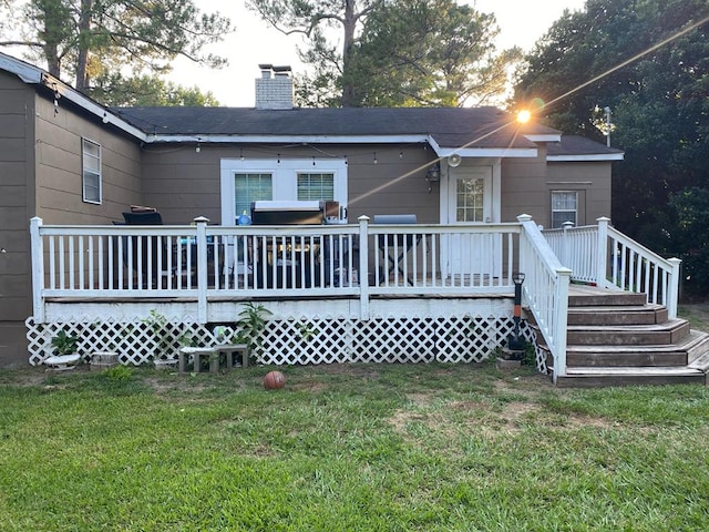 rear view of house featuring a yard, a wooden deck, and a chimney