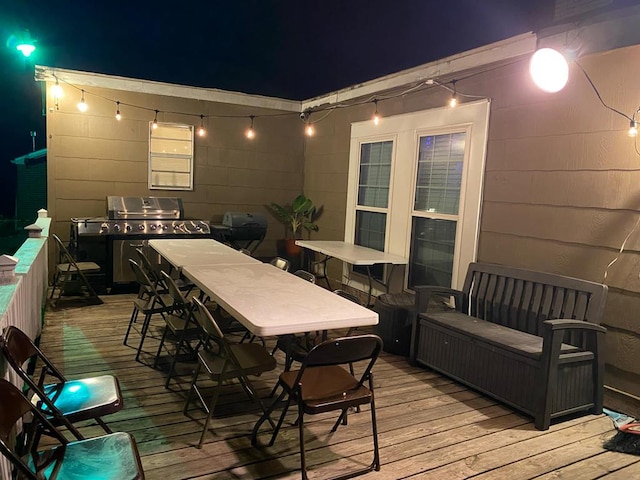 deck at twilight featuring a grill and outdoor dining area