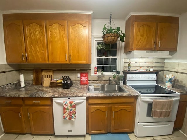 kitchen featuring white appliances, a sink, decorative backsplash, under cabinet range hood, and brown cabinets