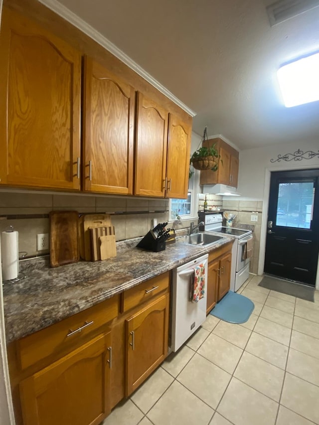 kitchen with light tile patterned flooring, brown cabinets, white appliances, and under cabinet range hood