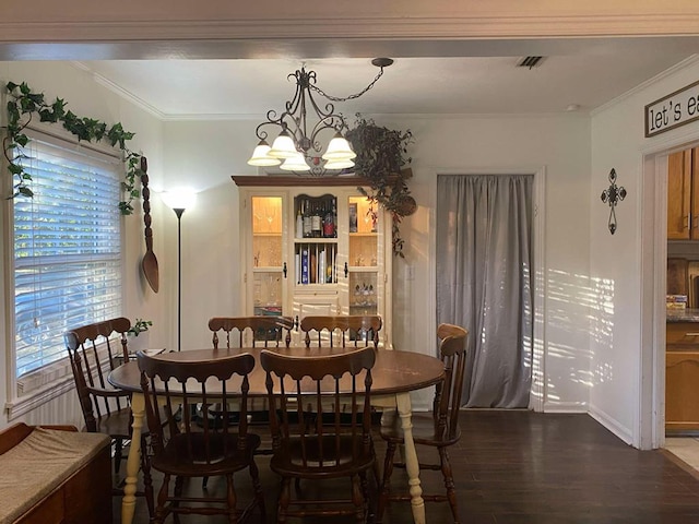 dining room featuring visible vents, a notable chandelier, wood finished floors, and ornamental molding