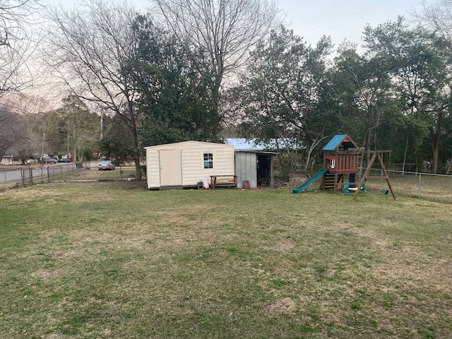 view of yard featuring fence, an outdoor structure, a shed, and a playground