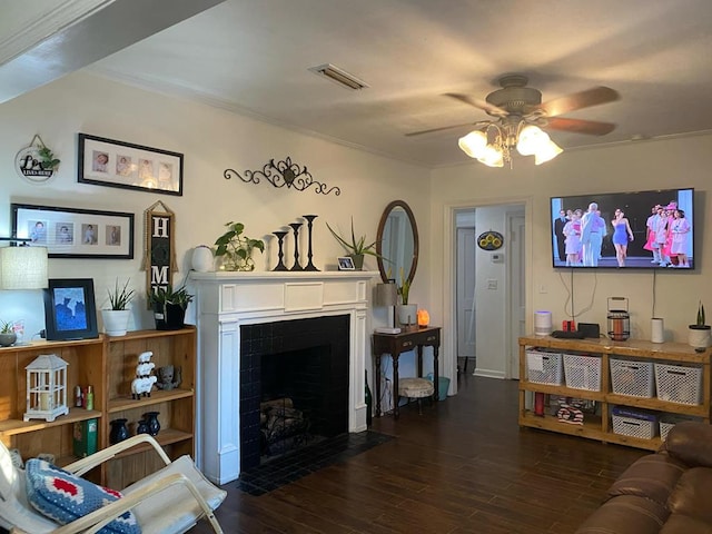 living area with visible vents, a fireplace with flush hearth, ornamental molding, wood finished floors, and a ceiling fan