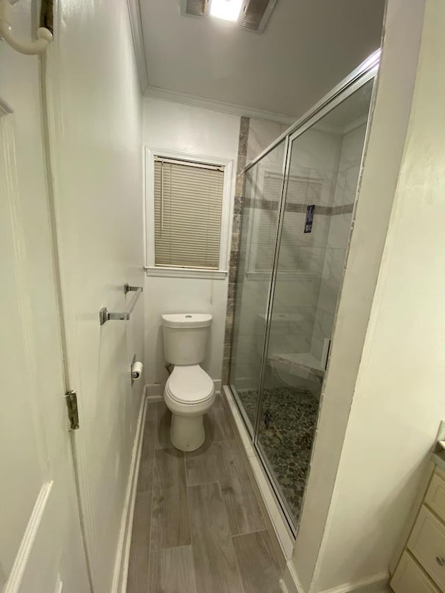 full bathroom with vanity, wood finish floors, a stall shower, ornamental molding, and toilet