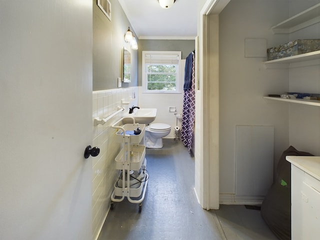 bathroom featuring toilet, tile walls, crown molding, and sink