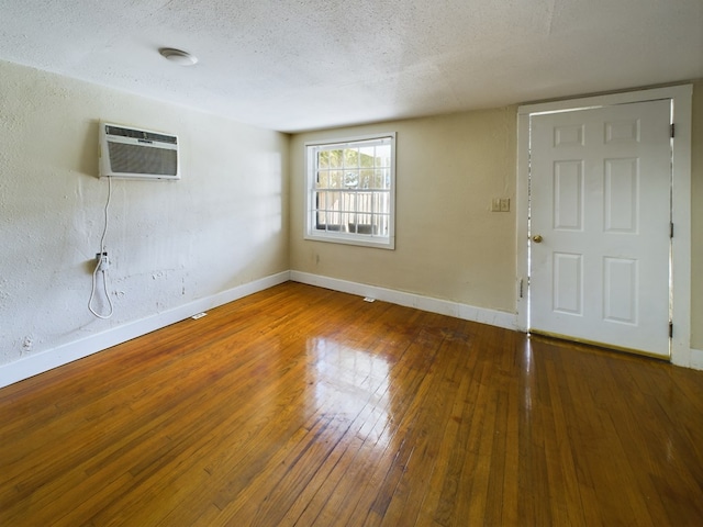 foyer entrance featuring a wall unit AC, wood-type flooring, and a textured ceiling