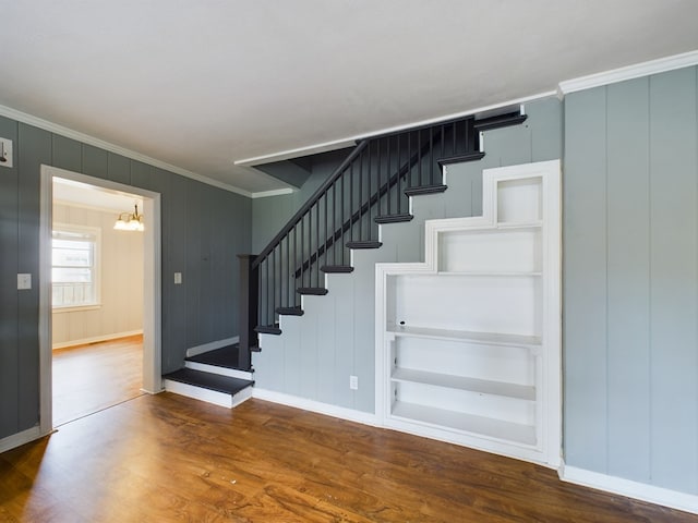 staircase with hardwood / wood-style flooring, ornamental molding, and a chandelier