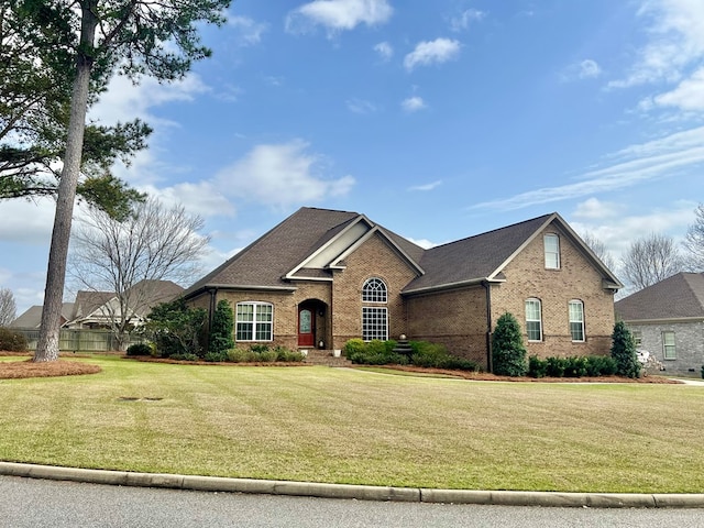 traditional-style house featuring a front lawn and brick siding