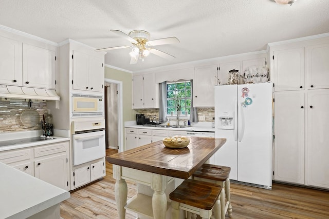 568 N Morris St, Slocomb, AL 36375 - kitchen featuring white appliances, light wood-type flooring, white cabinets, ceiling fan, and crown molding