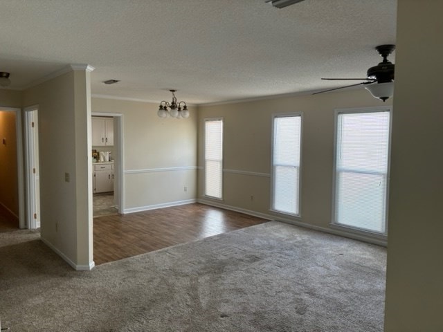 empty room featuring a textured ceiling, plenty of natural light, wood-type flooring, and ornamental molding