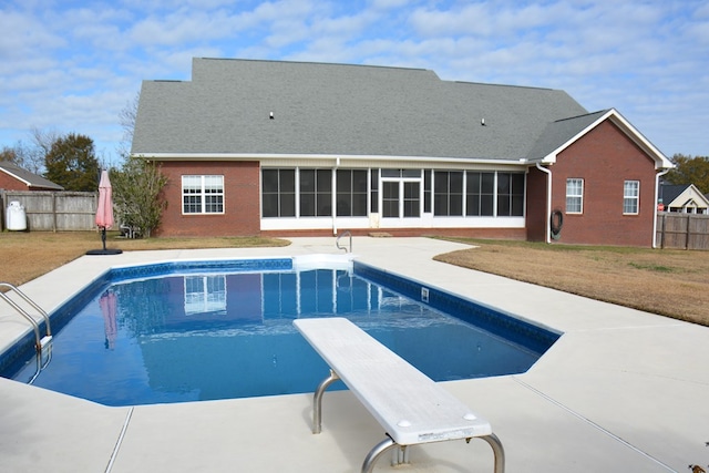 view of swimming pool featuring a sunroom, a diving board, a yard, and a patio