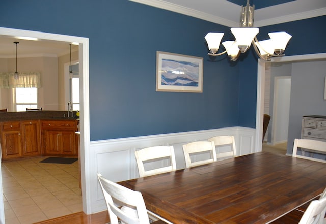 dining space featuring crown molding, sink, light wood-type flooring, and a notable chandelier