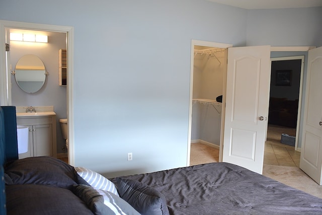 bedroom featuring a spacious closet, sink, ensuite bathroom, light colored carpet, and a closet