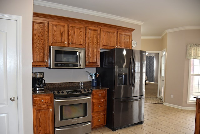 kitchen with light tile patterned floors, ornamental molding, stainless steel appliances, and dark stone counters