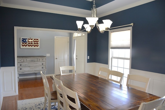 dining area with hardwood / wood-style floors, ornamental molding, and an inviting chandelier