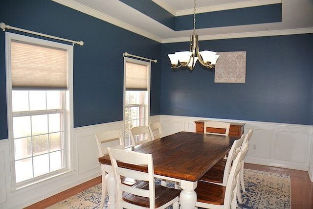 dining space with a notable chandelier, wood-type flooring, crown molding, and a wealth of natural light