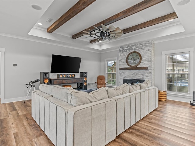 living room with visible vents, wood finished floors, ceiling fan, a tray ceiling, and a large fireplace