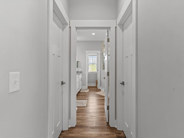 hallway featuring baseboards, recessed lighting, and dark wood-type flooring