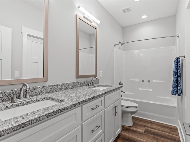bathroom featuring a sink, toilet, wood finished floors, and visible vents