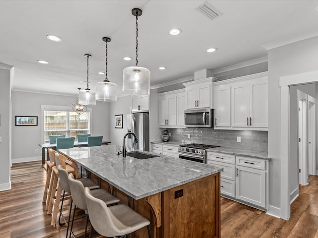 kitchen with backsplash, crown molding, a sink, baseboards, and stainless steel appliances