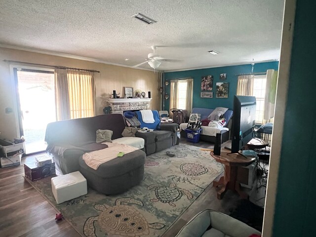 living room with hardwood / wood-style flooring, ceiling fan, crown molding, and a textured ceiling