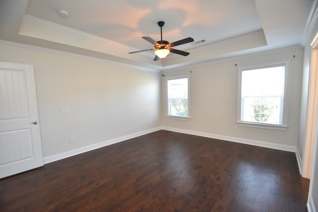 unfurnished room featuring a tray ceiling, crown molding, and dark hardwood / wood-style floors