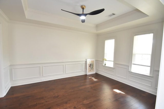 empty room featuring ceiling fan, a tray ceiling, dark hardwood / wood-style flooring, and ornamental molding