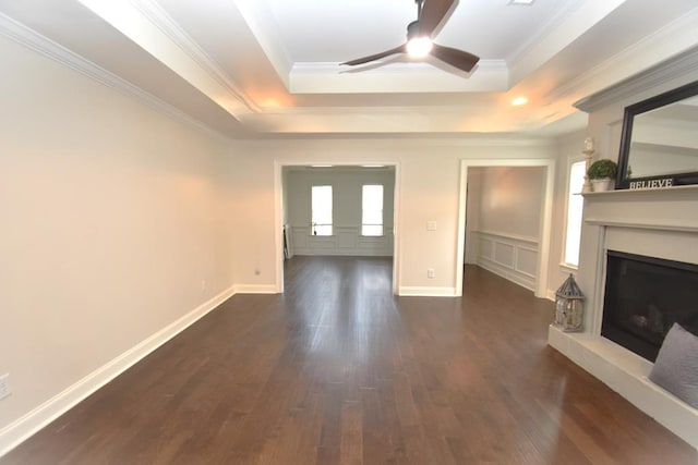 unfurnished living room with a tray ceiling, crown molding, and dark hardwood / wood-style floors