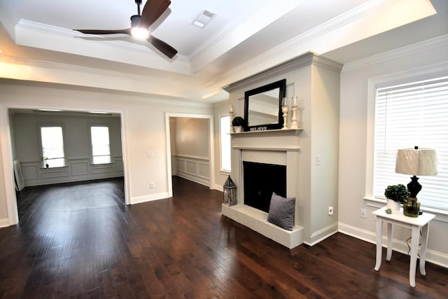 living room featuring dark hardwood / wood-style flooring, ornamental molding, a raised ceiling, and ceiling fan