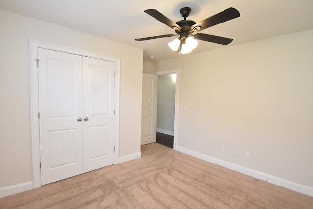 unfurnished bedroom featuring light carpet, ceiling fan, and a closet