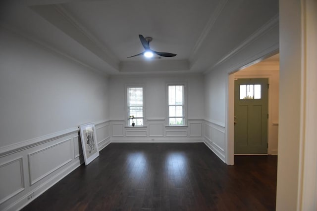 interior space with a raised ceiling, ceiling fan, dark hardwood / wood-style floors, and ornamental molding