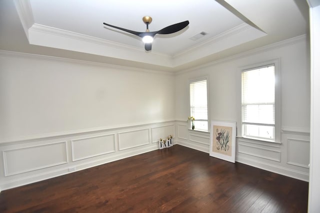 empty room with ceiling fan, a tray ceiling, dark wood-type flooring, and crown molding