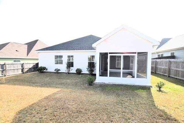 rear view of property featuring a yard and a sunroom