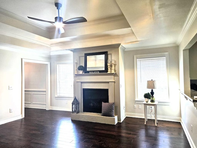 unfurnished living room featuring a tray ceiling, dark wood-type flooring, ornamental molding, and ceiling fan