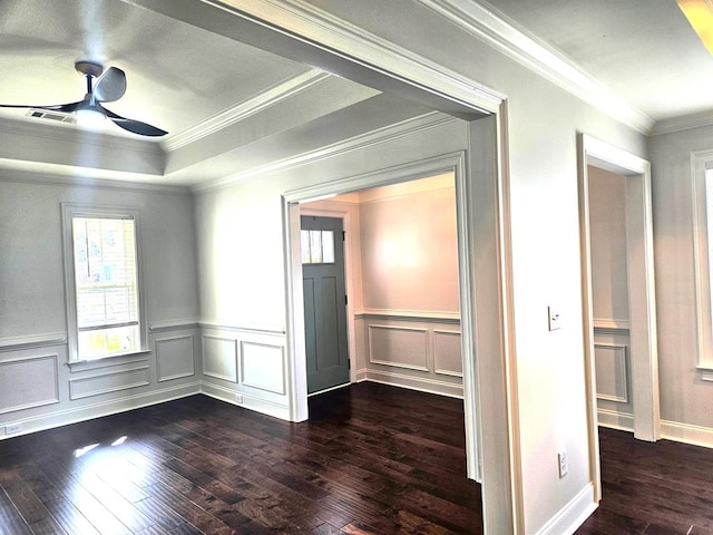 unfurnished room featuring a tray ceiling, dark wood-type flooring, ornamental molding, and ceiling fan