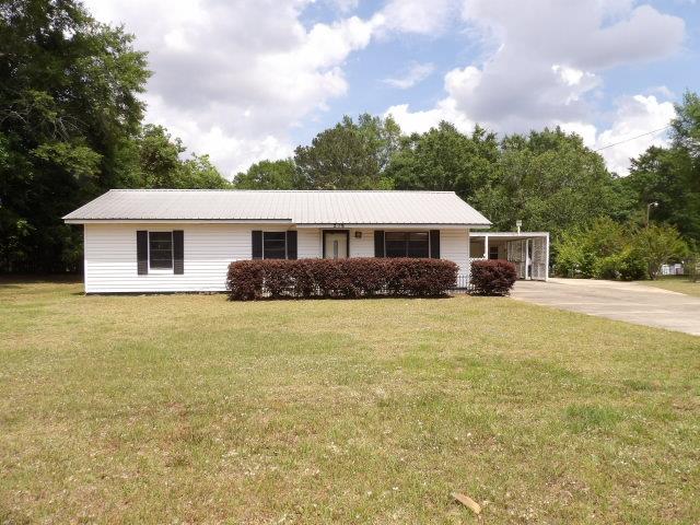 ranch-style house featuring driveway, metal roof, and a front yard