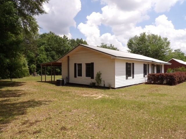 view of property exterior with central air condition unit and a yard