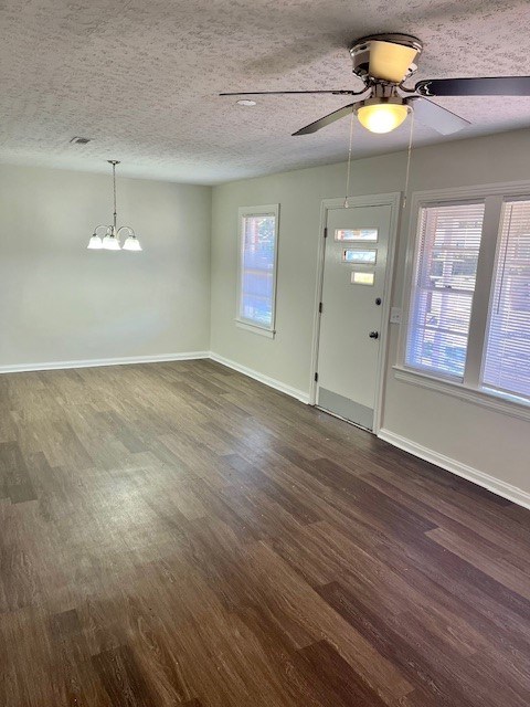 foyer with ceiling fan with notable chandelier, dark wood-type flooring, and a textured ceiling