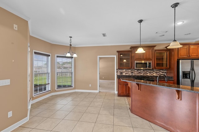 170 County Road 751, Enterprise, AL 36330 - kitchen with stainless steel appliances, a breakfast bar, brown cabinets, backsplash, and glass insert cabinets